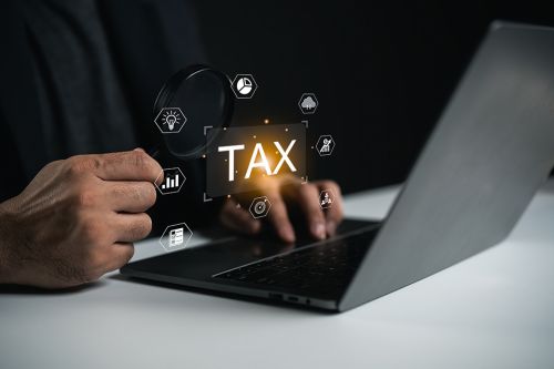 Geöffneter Laptop mit Schriftzug TAX darüber